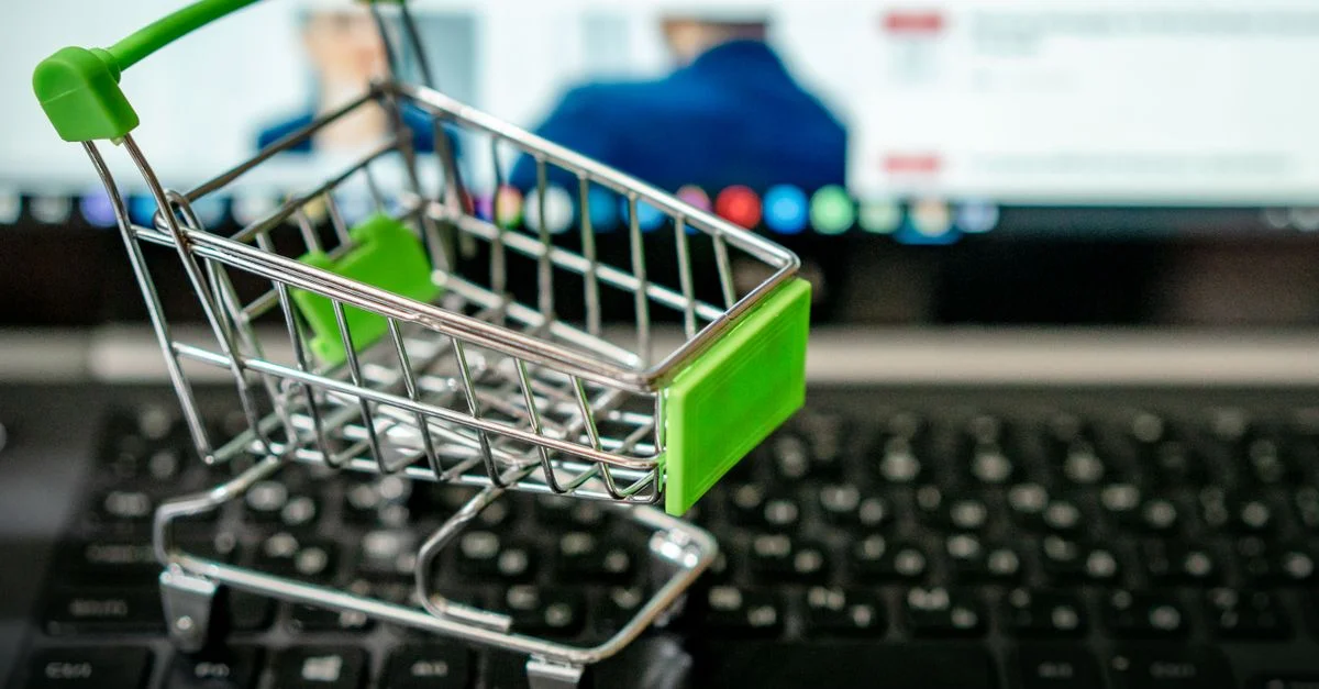 Mini chariot de shopping placé sur un clavier d'ordinateur portable, symbolisant le shopping en ligne.