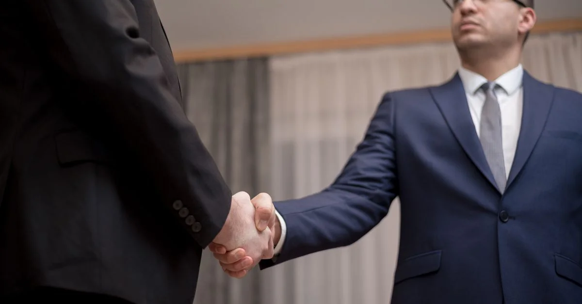 Deux hommes d'affaires en tenue formelle se serrant la main lors d'une réunion.