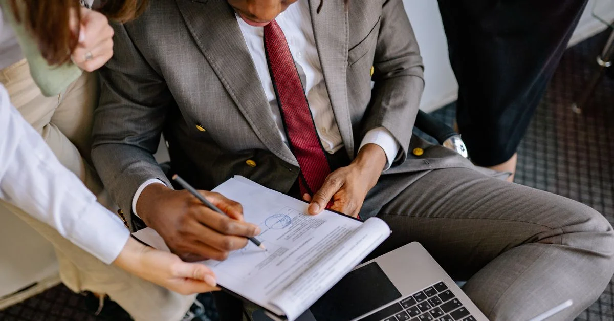Un homme d'affaires en costume signant un contrat avec l'aide de collègues.