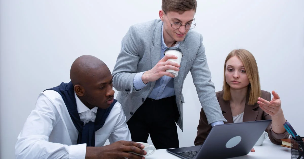 Équipe de professionnels collaborant autour d'un ordinateur portable dans un bureau.