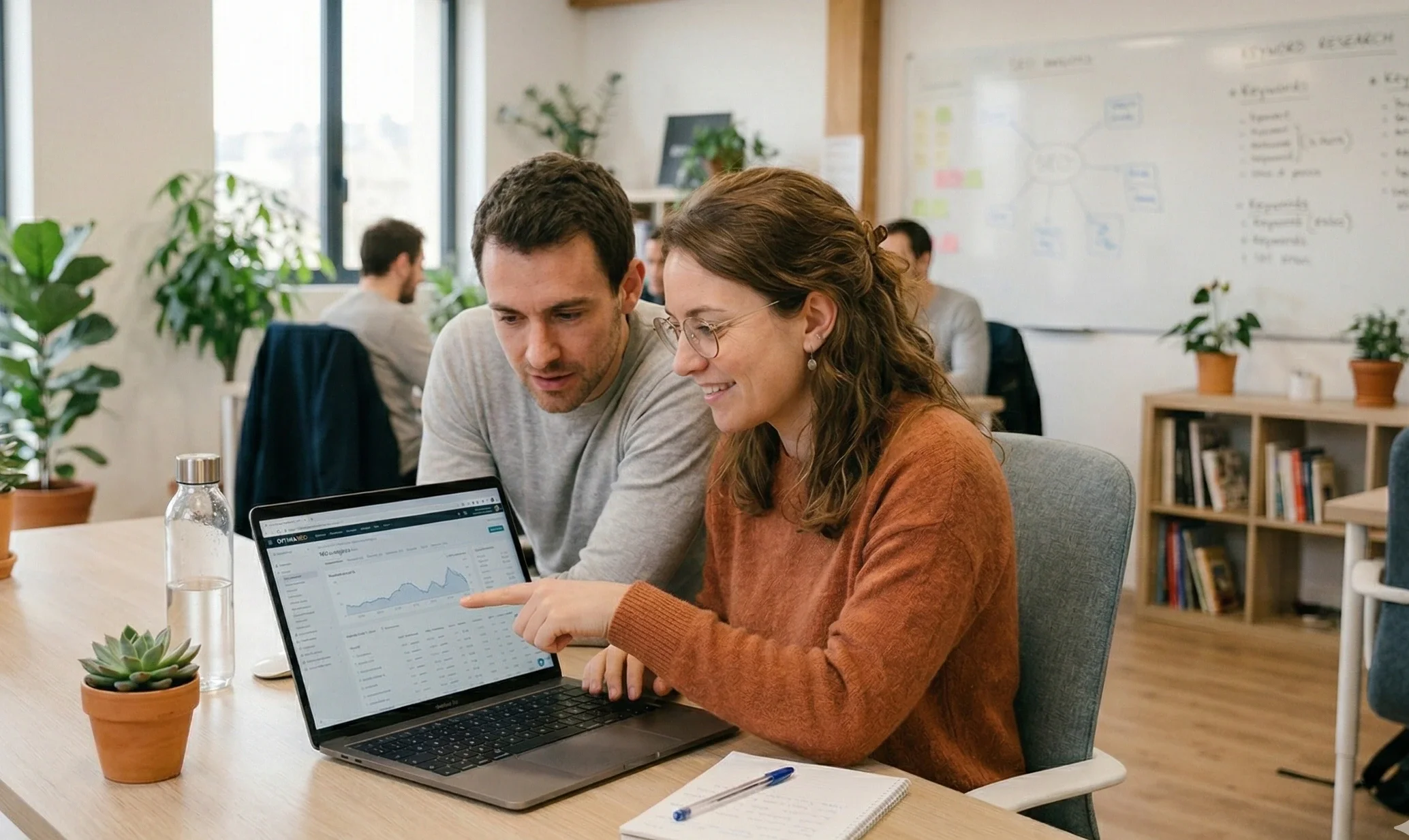 Consultant SEO freelance en rendez-vous avec une cliente pour un accompagnement personnalisé autour d'un ordinateur dans un bureau lumineux.