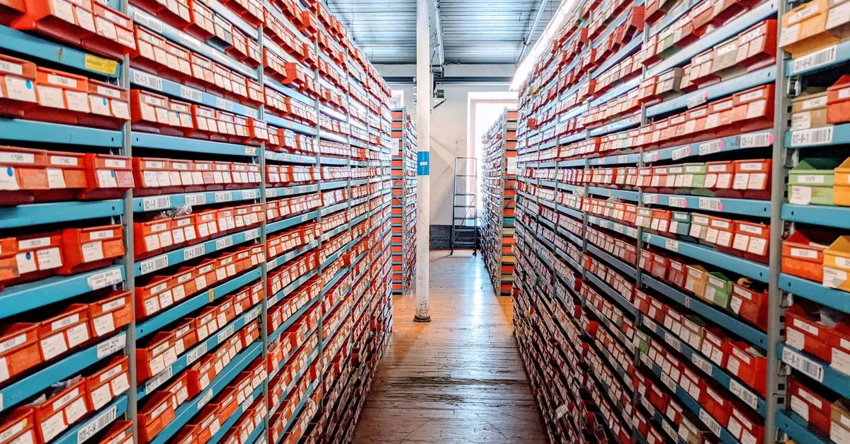 Une allée d'entrepôt bien organisée remplie de boîtes à chaussures rouges sur des étagères, mettant en valeur un stockage d'inventaire efficace.